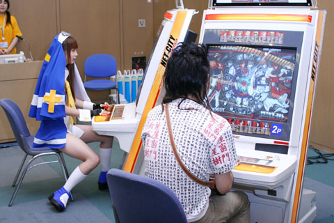 2girls arcade arcade_cabinet bridget_(guilty_gear) cosplay crossdressing guilty_gear lowres multiple_girls otaku photo playing_games video_game