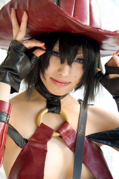 bare_shoulders black_gloves black_hair blue_eyes closed_mouth clothes_writing collarbone cosplay flat_chest gloves guilty_gear hair_between_eyes hand_on_headwear hands_up hat i-no lips looking_at_viewer nail_polish o-ring photo red_hat red_nails revealing_clothes short_hair simple_background solo upper_body white_background