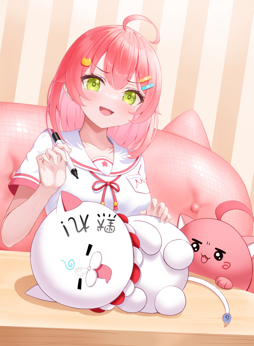 1girl 35p_(sakura_miko) absurdres ahoge bandaid_hair_ornament blush cat_hair_ornament collarbone commentary_request green_eyes hair_ornament highres holding holding_marker hololive kintoki_(sakura_miko) looking_at_viewer marker open_mouth pink_hair roina_(effj7473) sailor_collar sakura_miko sakura_miko_(6th_costume) shirt short_hair short_sleeves sitting smile virtual_youtuber white_sailor_collar white_shirt