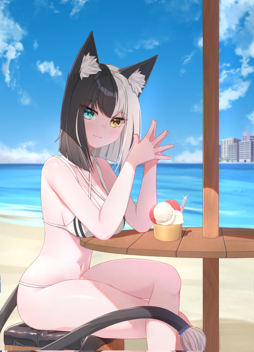 1girl :3 animal_ears aurahman beach bikini black_tail blue_eyes breasts cat_ears cat_girl cat_tail cleavage closed_mouth commentary crossed_legs english_commentary heterochromia highres ice_cream_cup looking_at_viewer medium_breasts medium_hair midriff multicolored_hair navel original own_hands_together sideboob sitting solo split-color_hair swimsuit tail two-tone_hair upper_body white_bikini white_hair yellow_eyes