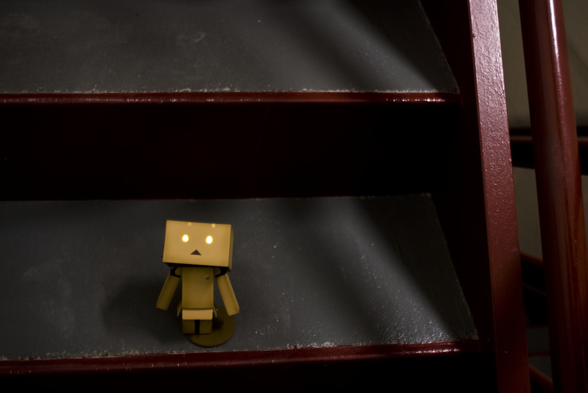absurdres box cardboard_box danboo figure full_body glowing glowing_eyes highres minimized photo source_request stairs standing toy triangle_mouth yotsubato!