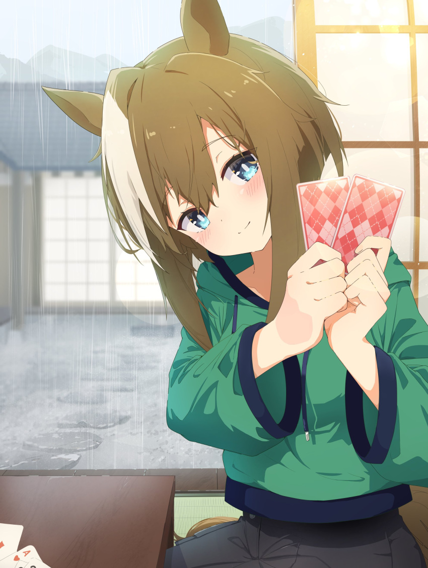 1girl absurdres animal_ears blue_eyes blush breasts brown_hair card cheval_grand_(umamusume) green_hoodie hair_between_eyes highres holding holding_card hood hood_down hoodie horse_ears horse_girl horse_tail long_sleeves looking_at_viewer multicolored_hair official_alternate_costume playing_card rain sagen sliding_doors smile solo streaked_hair table tail tatami umamusume white_hair wide_sleeves