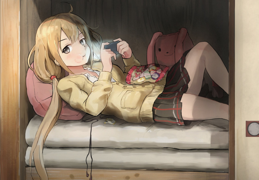 ahoge black_eyes black_skirt buttons candy candy_wrapper chewing commentary_request earbuds earphones earphones_removed food futaba_anzu handheld_game_console highres holding idolmaster idolmaster_cinderella_girls kamemaru light long_hair long_sleeves looking_at_viewer low_twintails lying on_back on_bed pillow playstation_portable pleated_skirt skirt solo stuffed_animal stuffed_bunny stuffed_toy sweater twintails wrapper
