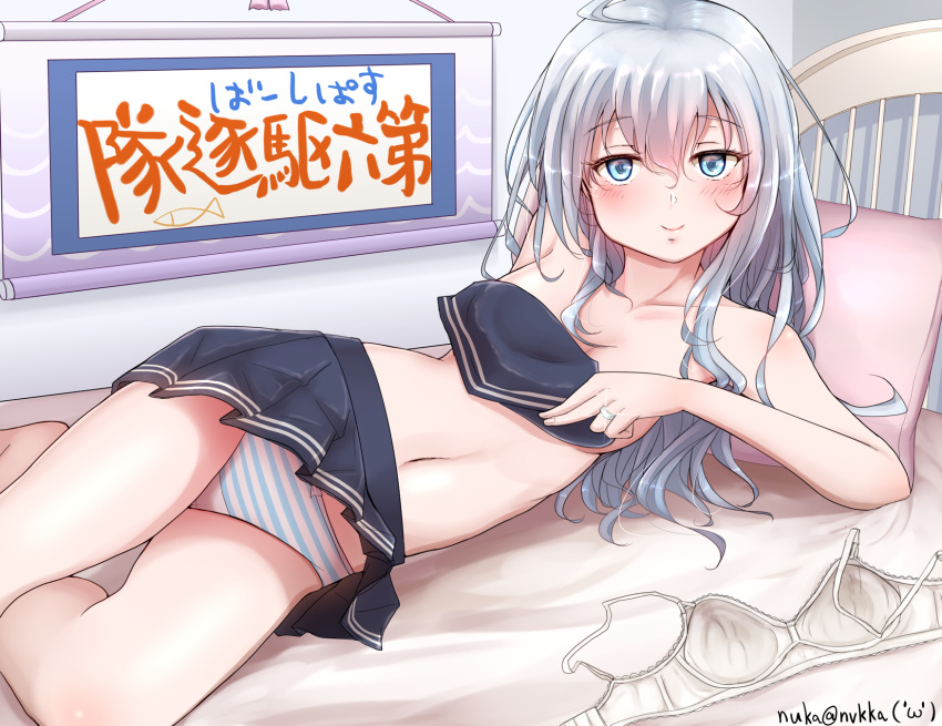 artist_name bed black_skirt blue_eyes blush bra bra_removed breasts closed_mouth collarbone commentary_request covering covering_breasts eyebrows_visible_through_hair flat_cap hair_between_eyes hat hibiki_(kantai_collection) highres jewelry kantai_collection long_hair looking_at_viewer miniskirt nuka_(nvkka) panties pillow pleated_skirt ring silver_hair skirt small_breasts smile solo striped striped_panties topless translation_request underwear wedding_band white_bra