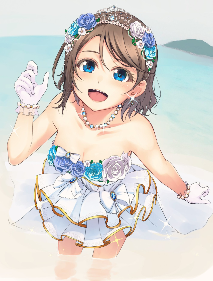 1girl :d beach blue_eyes blue_flower bow bracelet breasts brown_hair cleavage clenched_hands collarbone commentary_request day dress earrings flower gloves hair_flower hair_ornament highres jewelry looking_at_viewer love_live! love_live!_sunshine!! nanotsuki necklace open_mouth outdoors pearl_bracelet pearl_necklace smile solo sparkle strapless strapless_dress tiara wading waist_cape watanabe_you white_bow white_dress white_flower white_gloves