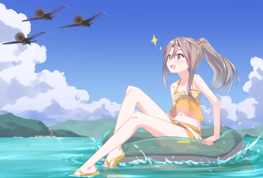 1girl aircraft alternate_costume bangs blush brown_eyes cloud day eyebrows_visible_through_hair flip-flops full_body gedoo_(gedo) hair_ornament hair_scrunchie high_ponytail highres innertube kantai_collection light_brown_hair long_hair mountain navel ocean open_mouth outdoors ponytail sandals scrunchie shorts sitting sky sleeveless solo sparkle swimsuit water zuihou_(kantai_collection)