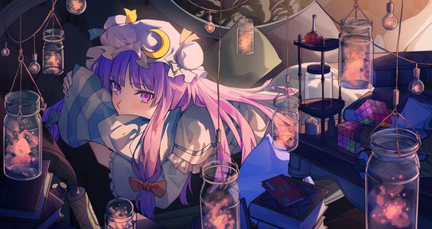 1girl absurdres bangs blue_bow blue_ribbon blush book_stack bow capelet commentary_request crescent crescent_moon_pin dress hair_bow hat hat_ribbon highres indoors jar long_hair long_sleeves lying mob_cap on_stomach patchouli_knowledge pillow pillow_hug pink_headwear pink_ribbon purple_eyes purple_hair red_bow ribbon solo touhou touhou_lost_word upper_body yangsan_(2991076090)