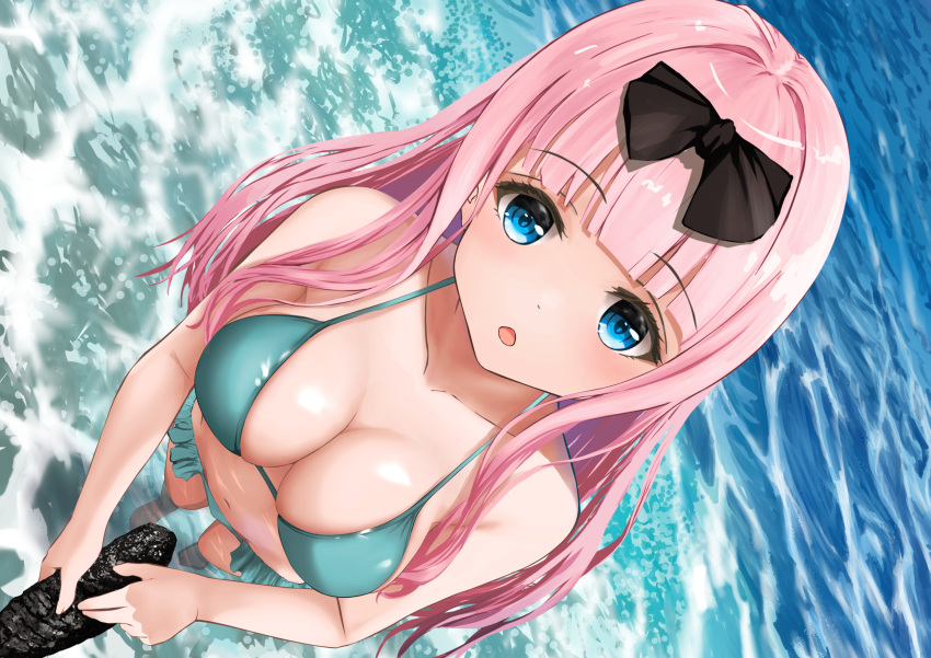 1girl :o bangs bare_shoulders bikini black_bow blue_eyes blunt_bangs blush bow breasts cleavage collarbone commentary_request day downblouse dutch_angle eyebrows_visible_through_hair frilled_bikini frills from_above fujiwara_chika gibun_(sozoshu) green_bikini hair_bow halterneck highres holding kaguya-sama_wa_kokurasetai_~tensai-tachi_no_renai_zunousen~ large_breasts looking_at_viewer looking_up navel ocean open_mouth outdoors phallic_symbol pink_hair sea_cucumber sexually_suggestive solo string_bikini swimsuit wading water