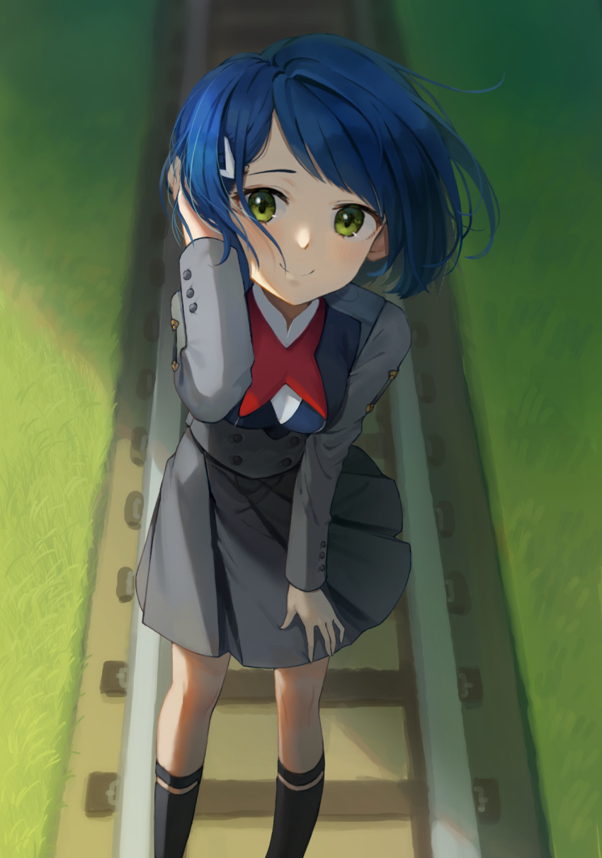 1girl adjusting_hair adjusting_skirt aeng_dyu black_legwear blue_hair blush bob_cut closed_mouth darling_in_the_franxx dress feet_out_of_frame floating_hair foreshortening grass green_eyes grey_dress hair_ornament hair_strand hairclip highres ichigo_(darling_in_the_franxx) kneehighs looking_at_viewer looking_up messy_hair outdoors perspective pleated_skirt railroad_tracks raised_eyebrows red_neckwear shaded_face shadow short_hair skirt smile socks solo uniform wind