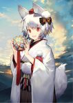  1girl akeome animal_ears ball bangs black_bow blue_sky bow chinese_zodiac cloud cloudy_sky hair_bow happy_new_year hat highres holding holding_ball inubashiri_momiji japanese_clothes kimono kitada_mo long_sleeves looking_at_viewer new_year open_mouth outdoors pom_pom_(clothes) red_eyes short_hair sky smile solo tail temari_ball tokin_hat touhou white_hair white_kimono wide_sleeves wolf_ears wolf_tail year_of_the_dog 