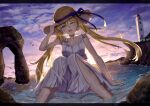  1girl absurdres artoria_caster_(fate) artoria_pendragon_(fate) bangs bare_shoulders beach blonde_hair blue_sky blush breasts collarbone dress fate/grand_order fate_(series) gradient_sky green_eyes hat highres lighthouse long_hair looking_at_viewer ocean one_eye_closed orange_sky shore sitting sky small_breasts smile solo straw_hat sunset thighs toukan twintails white_dress 