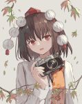  1girl bangs black_hair camera hat holding holding_camera leaf leaf_print long_sleeves looking_at_viewer maple_leaf_print ookashippo open_mouth pom_pom_(clothes) red_eyes red_headwear shameimaru_aya shirt solo tokin_hat touhou upper_body white_shirt 