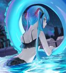  1girl bangs bikini black_bikini blue_eyes blue_hair city commentary facing_away frilled_bikini frills from_behind hair_ornament hatsune_miku highres innertube long_hair looking_back night night_sky open_mouth outdoors partially_submerged pool rerendi sky solo swimsuit twintails very_long_hair vocaloid water 
