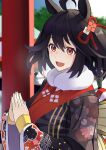  1girl absurdres animal_ears black_hair black_kimono blue_sky blurry blurry_background commentary_request floral_print fur-trimmed_kimono fur_trim hair_between_eyes hatsumoude highres horse_ears horse_girl japanese_clothes kimono kitasan_black_(umamusume) kouhaku_nawa long_sleeves looking_at_viewer obi open_mouth outdoors own_hands_together people red_eyes reibun_(raven1119) rope sash shimenawa shrine sky smile solo torii tree two_side_up umamusume visible_air 