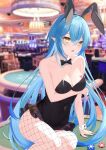  1girl :o absurdres ahoge animal_ears arm_support arm_under_breasts bare_shoulders black_bow black_bowtie black_leotard blue_hair blurry blurry_background bow bowtie breast_tattoo breasts casino collarbone covered_navel detached_collar fake_animal_ears fishnet_pantyhose fishnets frilled_leotard frills heart heart_ahoge heart_tattoo highres hololive jiang_ye_kiri large_breasts leaning_to_the_side leotard long_hair looking_at_viewer on_table open_mouth pantyhose playboy_bunny pointy_ears poker_chip poker_table rabbit_ears sitting solo table tattoo very_long_hair virtual_youtuber yellow_eyes yukihana_lamy 
