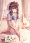  1girl bangs bare_legs barefoot bed blinds blush brown_hair collarbone commentary_request cup flower hair_between_eyes hair_ornament hair_scrunchie highres holding holding_cup indoors long_hair looking_at_viewer mug on_bed original pillow scrunchie shadow short_sleeves signature sitting smile solo tanihara_natsuki twintails yellow_eyes 