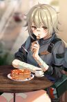  1girl absurdres aqua_hair bandaged_arm bandages bangs blurry blurry_background commission crossed_arms cup feet_out_of_frame food girls&#039;_frontline highres hs2000_(girls&#039;_frontline) kakao346 looking_at_viewer open_mouth orange_eyes pancake pixiv_request short_hair sitting sleeves_rolled_up solo table tactical_clothes 