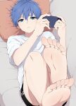  1boy barefoot bishounen black_shorts blue_eyes blue_hair cellphone closed_mouth couch facing_viewer feet foot_focus from_above hair_between_eyes highres hiraganako2525 holding holding_phone looking_at_viewer looking_up lying male_focus on_back original phone pillow shirt short_hair short_sleeves shorts smartphone toes white_shirt 