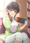  1girl ;d black_hair book bookshelf breasts commentary_request green_jacket hair_tucking hands_up holding indoors jacket knees_together_feet_apart long_hair long_sleeves looking_at_viewer medium_breasts niichi_(komorebi-palette) nintendo_switch one_eye_closed open_clothes open_jacket original pants puffy_long_sleeves puffy_sleeves red_eyes shirt sitting smile solo white_pants white_shirt 