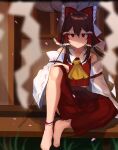  1girl ankle_ribbon ascot bangs barefoot blurry blurry_background bow brown_hair cherry_blossoms closed_mouth depth_of_field detached_sleeves expressionless falling_petals feet frilled_bow frills hair_bow hair_tubes hakurei_reimu highres leg_ribbon long_hair looking_at_viewer majime_joe petals red_bow red_eyes red_skirt ribbon ribbon-trimmed_sleeves ribbon_trim sitting skirt toes touhou 