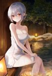  1girl bangs bare_arms bare_shoulders breasts cleavage closed_mouth collarbone expressionless fence grey_hair hair_between_eyes hair_bun heeri highres holding_cloth lamp looking_at_viewer looking_to_the_side medium_breasts mole mole_under_eye naked_towel night onsen original outdoors red_eyes ripples short_hair sidelocks single_hair_bun single_side_bun sitting snow soaking_feet solo thighs towel tree water wet white_towel wooden_fence 