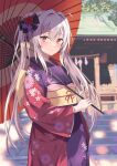  1girl blurry blurry_background blush floral_print flower grey_hair hair_between_eyes hair_flower hair_ornament highres holding holding_umbrella japanese_clothes kimono long_hair looking_at_viewer new_year obi oil-paper_umbrella original outdoors ponytail purple_kimono rasahan red_eyes red_kimono sash solo umbrella wide_sleeves 