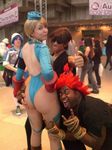  2boys 5girls \m/ ass ass_grab bangs blonde_hair cammy_white cammy_white_(cosplay) capcom cosplay gouki gouki_(cosplay) hand_on_hip huge_ass ikuy leotard long_hair looking_at_viewer looking_back multiple_boys multiple_girls no_bra open_mouth photo real sakuracon street_fighter thong_leotard twin_braids 