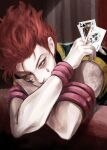 1boy card commentary_request facepaint highres hisoka_morow holding holding_card hunter_x_hunter joker_(card) king_(playing_card) korean_commentary leaning_on_object male_focus nwocp playing_card red_hair short_hair sitting solo table upper_body yellow_eyes 