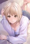  1girl barefoot blue_shorts breasts brown_eyes cleavage collarbone crossed_ankles hand_in_own_hair highres legs_up light_brown_hair looking_at_viewer lying on_stomach original pasdar pillow shirt shorts smile white_shirt 
