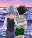  186x6 2boys bare_shoulders black_hair from_behind gon_freecss green_shorts hand_on_another&#039;s_shoulder highres hunter_x_hunter killua_zoldyck looking_afar male_child male_focus multiple_boys ocean outdoors shirt short_hair shorts sleeveless spiked_hair white_hair white_shirt 