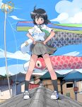  1girl antenna_hair black_hair black_socks blue_footwear cloud cloudy_sky full_body green_eyes grey_skirt hands_on_own_hips highres house koinobori looking_at_viewer masuki open_mouth original outdoors pleated_skirt rooftop shirt shoes short_hair skirt sky sneakers socks solo standing white_shirt wind windsock 