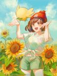  1girl :d absurdres beanie brown_hair cloud commentary_request day floral_print flower green_shorts hands_up happy hat highres open_mouth outdoors pokemon pokemon_(creature) pokemon_(game) pokemon_sm red_headwear rowlet selene_(pokemon) shirt short_shorts short_sleeves shorts sky smile sunflower t-shirt teeth tied_shirt tongue zhongmu 