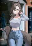  1girl animal_ears arknights bag blurry blurry_background breasts brown_hair casual cellphone commentary cowboy_shot crop_top denim extra_ears grey_shirt hair_behind_ear hair_over_shoulder handbag highres holding holding_clothes holding_jacket holding_phone jacket jeans large_breasts long_hair looking_at_viewer low-tied_long_hair maanu midriff mole_above_eye navel pants penance_(arknights) phone shirt smartphone solo tail window wolf_ears wolf_girl wolf_tail yellow_eyes 