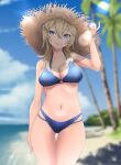  1girl bare_arms bare_legs bare_shoulders beach bikini blonde_hair blue_bikini blue_eyes blurry blurry_background breasts brown_headwear collarbone cowboy_shot day hair_between_eyes hat highres kantai_collection large_breasts long_hair neko_no_hige ocean open_mouth outdoors palm_tree smile solo straw_hat swimsuit thigh_gap tree tuscaloosa_(kancolle) 