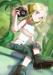  1girl ankle_boots belt blonde_hair boots breasts camera capri_pants closed_mouth commentary_request crossed_legs day dusk_poke27 from_below green_eyes green_pants highres holding holding_camera looking_down outdoors palm_tree pants photographer pokemon pokemon_(game) pokemon_xy shirt sitting sleeveless sleeveless_shirt smile solo tree viola_(pokemon) white_belt white_shirt 