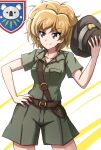  1girl belt blue_eyes brown_belt closed_mouth collared_shirt commentary cowboy_shot girls_und_panzer green_shirt green_shorts hand_on_own_hip hat highres holding holding_clothes holding_hat kamonohashi_(girls_und_panzer) koala_forest_(emblem) koala_forest_military_uniform looking_to_the_side messy_hair omachi_(slabco) orange_hair sam_browne_belt shirt short_hair short_sleeves shorts slouch_hat smile solo standing unworn_hat unworn_headwear 