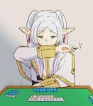  1girl alone_comic arm_rest capelet commentary_request earrings elf frieren green_eyes highres holding_mahjong_tile jewelry long_hair looking_at_object mahjong mahjong_tile parted_bangs pointy_ears shirt simple_background solo sousou_no_frieren striped striped_shirt twintails white_capelet white_hair 