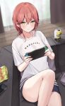  1girl black_shorts blush breasts can cellphone chips_(food) collarbone couch food highres kaetzchen large_breasts liliya_(kaetzchen) long_hair looking_at_viewer nintendo_switch original phone potato_chips red_hair shirt short_sleeves shorts sitting solo strong_zero thighs white_shirt yellow_eyes 