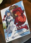 2girls :o arm_support ass ayanami_rei bangs blue_hair blush bodysuit book bracer breasts brown_hair clenched_teeth cover covered_nipples dated dutch_angle evangelion:_2.0_you_can_(not)_advance full_body gloves hair_between_eyes hair_ornament hand_on_hip highres knee_up kneeling leaning_forward long_hair looking_at_viewer looking_back multiple_girls neon_genesis_evangelion number open_mouth photo pilot_suit plugsuit rebuild_of_evangelion red_eyes see-through shikinami_asuka_langley short_hair sitting small_breasts souryuu_asuka_langley surprised teeth test_plugsuit turtleneck twintails white_bodysuit yasuda_akira 