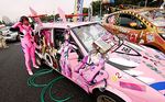  bodysuit car carpark comedy cosplay crossdressing funny hose itasha japan japanese_banner makinami_mari_illustrious makinami_mari_illustrious_(cosplay) motor_vehicle neon_genesis_evangelion photo real road soryu_asuka_langley souryuu_asuka_langley vehicle 