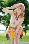  belt bracelet cosplay female final_fantasy final_fantasy_xiii grass jewelry looking_at_viewer midriff necklace oerba_dia_vanille oerba_dia_vanille_(cosplay) outdoors pink_shirt shirt skirt solo standing tree twintails 