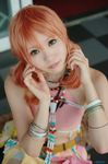  1girl beads belt bracelet cosplay female final_fantasy final_fantasy_xiii jewelry looking_at_viewer midriff necklace oerba_dia_vanille oerba_dia_vanille_(cosplay) pink_shirt shirt sitting solo twintails 