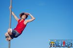  1boy black_hair blue_sky climbing copyright_name cosplay denim denim_shorts hat male male_focus monkey_d_luffy monkey_d_luffy_(cosplay) one_piece photo pole red_vest sandals shorts sky solo straw_hat title_drop vest 