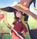  1girl alaskastomatoez black_cape black_gloves black_hair cape closed_mouth day dress fence fingerless_gloves gloves grass hat highres holding holding_staff kono_subarashii_sekai_ni_shukufuku_wo! long_hair mage_staff megumin off-shoulder_dress off_shoulder outdoors red_dress red_eyes sky solo staff witch_hat wooden_fence 