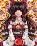  apple ascot bow brown_eyes brown_hair collarbone detached_sleeves embellished_costume floral_background floral_print food fruit hair_bow hair_tubes hakurei_reimu kabaji large_bow ribbon-trimmed_sleeves ribbon_trim solo touhou upper_body 