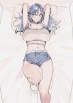  1girl arms_behind_head arms_up bed blue_hair blue_shorts blush breasts cleavage closed_mouth goshiki_suzu grey_tank_top highres huge_breasts long_hair lying mole mole_under_eye navel on_back on_bed original pillow short_shorts shorts socks solo sweat tank_top tokiwa_nao 