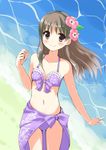  2015 atelier_(series) atelier_totori beach bikini blush bow brown_eyes brown_hair collarbone cowboy_shot dated flower front-tie_bikini front-tie_top hair_flower hair_ornament halterneck hibiscus long_hair minidraco navel number outdoors purple_bikini purple_bow purple_sarong ribbon-trimmed_bikini sarong signature smile solo swimsuit totooria_helmold water 