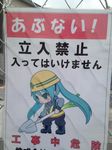  1girl construction_site fence hardhat hatsune_miku helmet photo shovel solo spring_onion translation_request vocaloid warning_sign what 