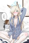  1girl animal_ears barefoot blonde_hair blue_archive blue_eyes blue_shirt breasts collared_shirt commentary_request dog_ears hair_over_one_eye halo highres kanna_(blue_archive) long_hair looking_at_viewer medium_breasts naked_shirt okara on_bed sharp_teeth shirt sitting solo teeth translation_request 