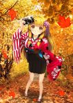  autumn autumn_leaves bangs blonde_hair blunt_bangs blush camera contrapposto e_neko floral_print flower full_body geta hair_flower hair_ornament hair_ribbon highres japanese_clothes long_hair long_sleeves looking_at_viewer photo_background pleated_skirt ribbon skirt smile solo standing tabi tress_ribbon wide_sleeves yellow_eyes 